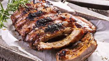 A rack of ribs on a wooden tray with a sprig of rosemary.