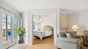 Quarto moderno com cama, mesa de cabeceira, abajur e vista para o exterior.