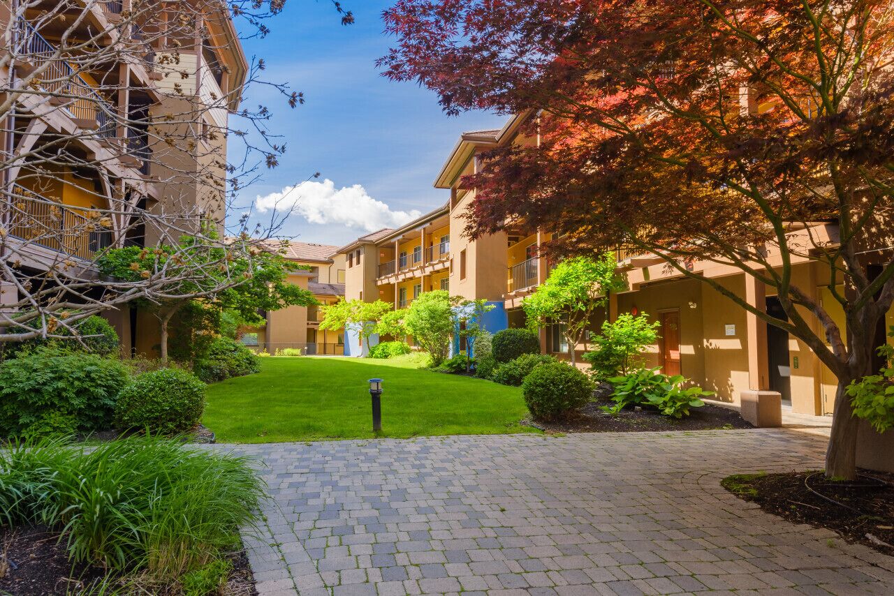 A courtyard with a paved walkway, surrounded by multi-story buildings with balconies.