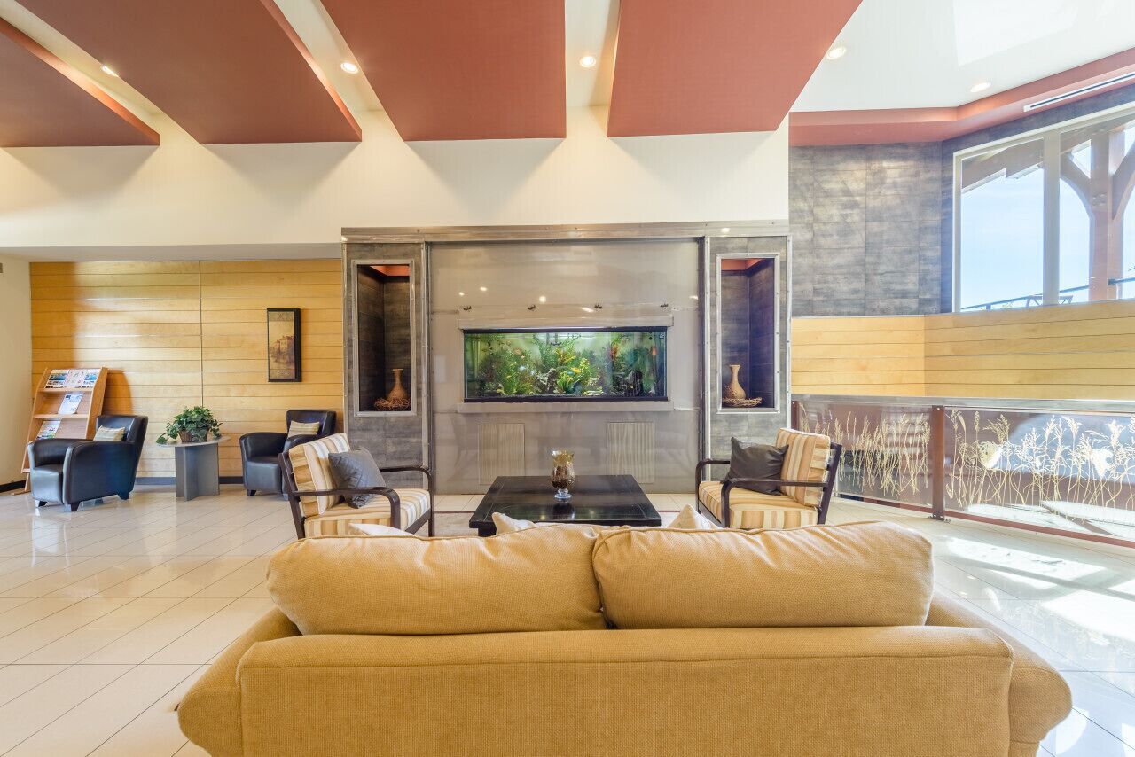 A modern lobby with a large aquarium, comfortable seating, and a view of the outdoors.