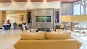 Un vestíbulo moderno con un gran acuario, asientos cómodos y vistas al exterior.