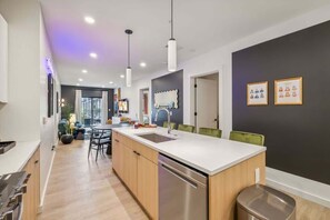 A modern kitchen with a central island, stainless steel appliances, and pendant lighting.