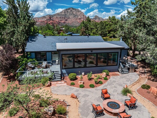 A modern house with a large deck, outdoor seating, and a fire pit.