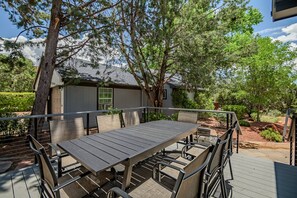 A patio with a table and chairs, surrounded by trees and a small building.