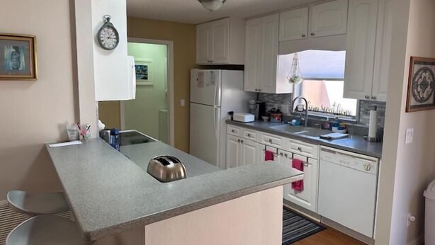 A modern kitchen with white cabinets, a stainless steel toaster, and a refrigerator. - 2 bed/2bath Courtyard Villa Spanish Springs w/cart (The Villages)