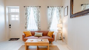 A living room with a sofa, coffee table, and a lamp. - Cozy, walkable 1-bedroom apartment in Pittsburgh with WiFi, AC (Pittsburgh)