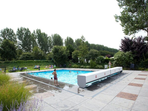 A swimming pool with a water slide, surrounded by a garden and trees. - Nice Tent With Bathroom, Near a Recreation Area (Noord-Scharwoude)