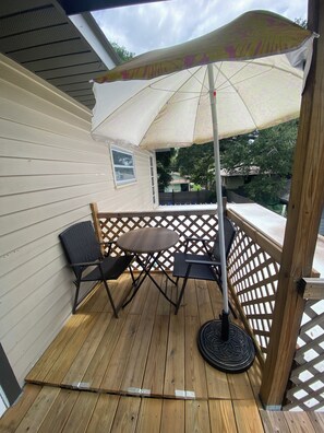 Um deck de madeira com mesa, cadeiras, um guarda-sol e um cercado de madeira.