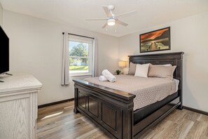 A bedroom with a bed, a ceiling fan, a window, and a painting on the wall. - Palm Bay 3BR Home | Screened Patio + Workspace (Palm Bay)