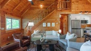 A wooden cabin interior with a living area, a staircase, and a kitchen. - Luxury Renovated | Lake & Mountain Views | Hot Tub (Fannin County)