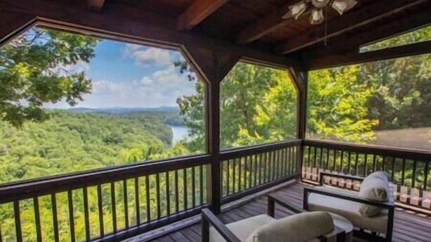 A covered outdoor deck with a view of a forest and a river. - Luxury Renovated | Lake & Mountain Views | Hot Tub (Fannin County)