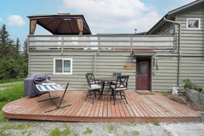 Une terrasse avec une table et des chaises, un barbecue et un espace abrité.