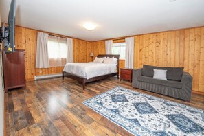 Une chambre avec un plancher en bois, un lit, un canapé et un tapis.