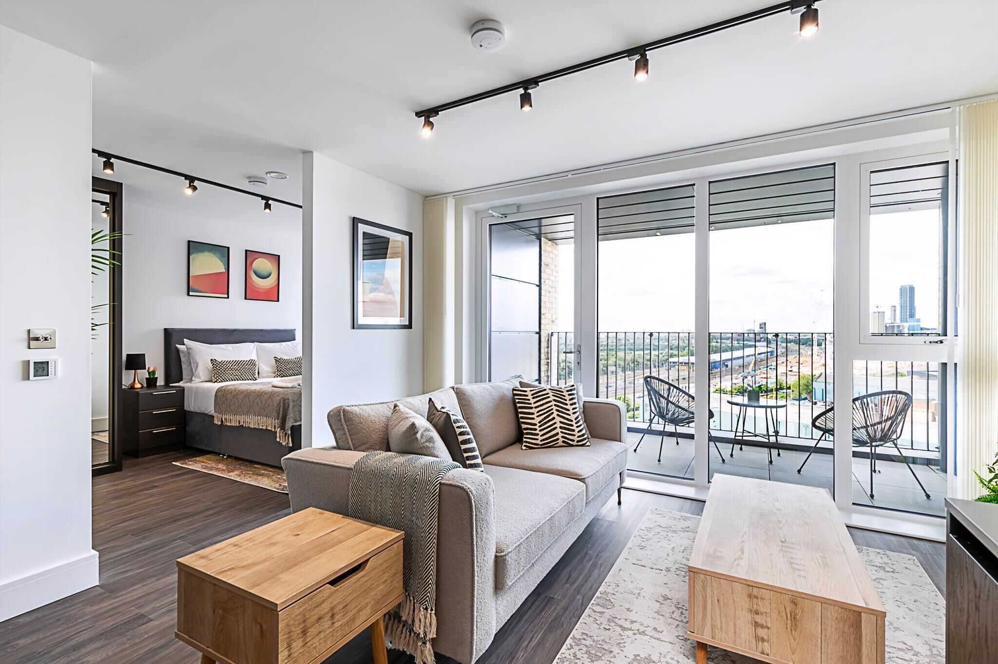 A modern living room with a sofa, coffee table, and a balcony with outdoor seating.