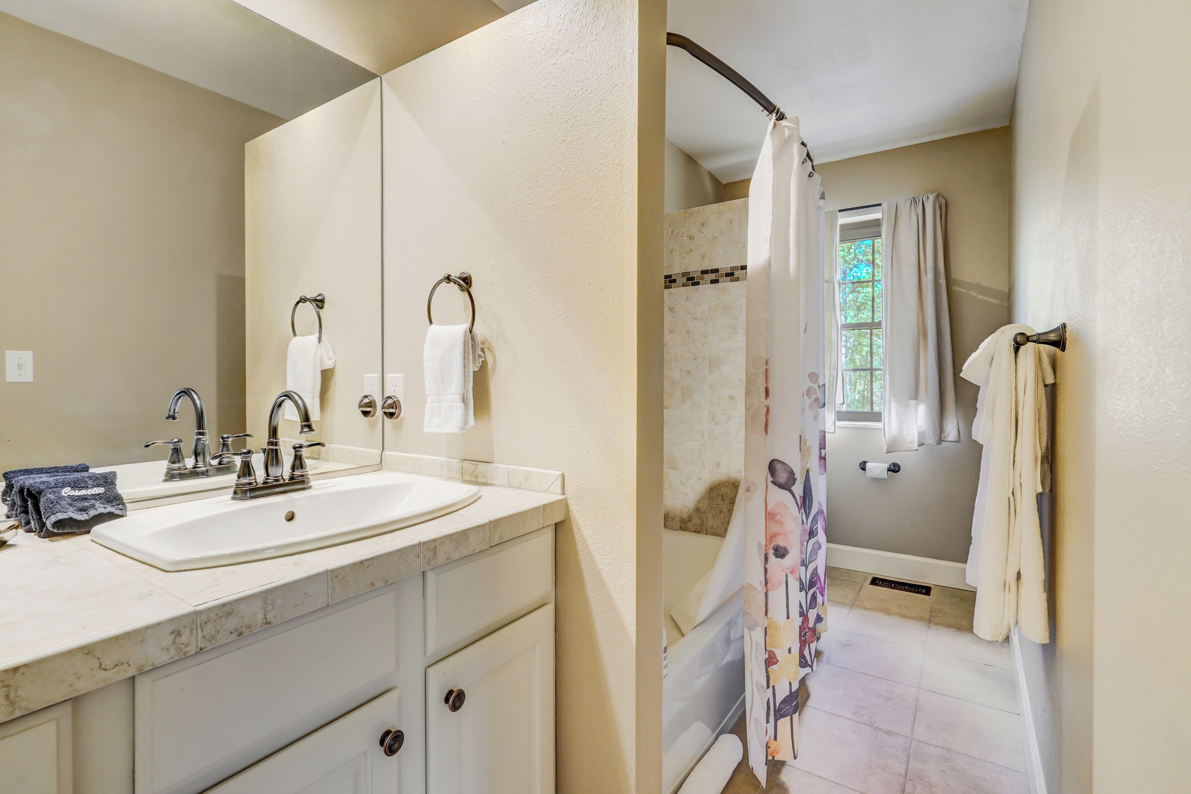 A bathroom with a large mirror, a sink, and a shower area.