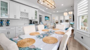 A spacious kitchen with white cabinetry, a coffee bar, and a dining area with a large table and woven placemats. - 5BR/3.5BA Steps to Beach - Sleeps 12 (Atlantic City)