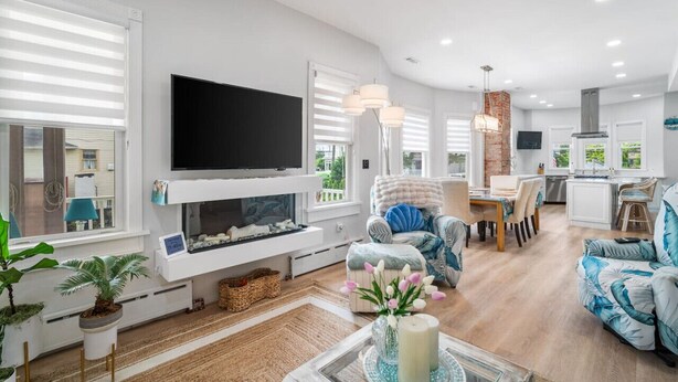 A modern living room with a flat-screen TV, comfortable seating, a fireplace, and a kitchen area. - 5BR/3.5BA Steps to Beach - Sleeps 12 (Atlantic City)