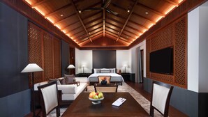 A hotel room with a wooden ceiling, a large bed, a TV, a dining table with chairs, and a fruit bowl. - Ahnluh Guantang Hotel (Chengdu)