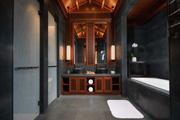Een moderne badkamer met een houten wastafelmeubel, een grote spiegel en een ligbad.