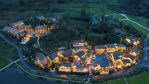 An aerial view of a well-lit resort with multiple buildings, a winding road, and surrounding greenery. - Ahnluh Guantang Hotel (Chengdu)