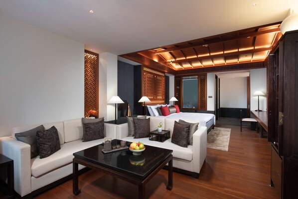Een moderne hotelkamer met een bank, een eettafel, een bed en een houten plafond.