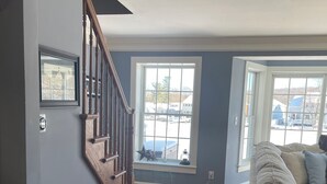 A spacious living room with hardwood flooring, a beige sofa, and a staircase with wooden railings.