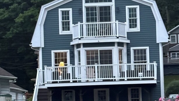 A two-story house with a balcony, a covered deck, and a dock extending into the water.