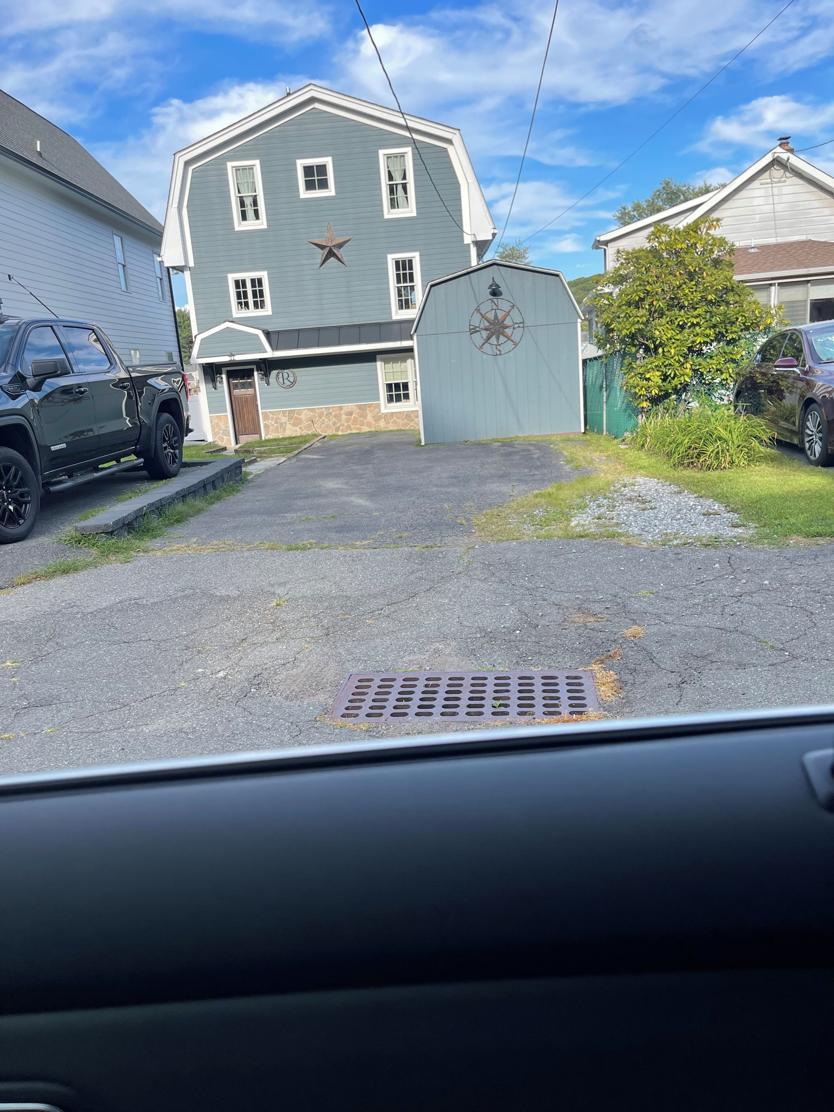 A residential driveway with a house, a garage, and a large metal gate with a compass design.