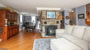 A living room with a fireplace, a sofa, a dining area with chairs, and a wooden cabinet.