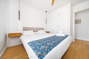 Ein Schlafzimmer mit Bett, Nachttischen, einem Holzkopfende, einem Deckenventilator und einer Tür mit Fliesendekor.