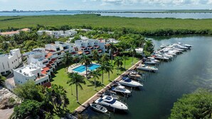 Ein Resort mit Schwimmbad, mehreren Booten, die am Wasser liegen, und einer Brücke im Hintergrund.