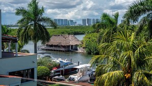 Un port de plaisance avec des bateaux amarrés, une construction à toit de chaume et, en arrière-plan, le profil de la ville.