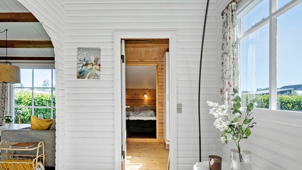 A cozy room with a wooden ceiling, a bed, a small table with a vase, and a view of greenery outside. - Amazing home in Væggerløse with WiFi (Væggerløse)