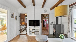 A cozy living room with a TV, wooden beams, a fireplace, and a dining area with a table and chairs. - Amazing home in Væggerløse with WiFi (Væggerløse)