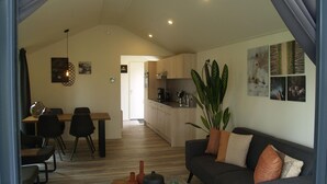 A modern living room with a sofa, coffee table, and dining area. - Comfortable Chalet, in a Beautiful Holiday Park (Ruinen)