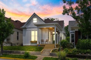 Une maison à deux étages avec un porche à l’avant, un garage et une pelouse bien entretenue.