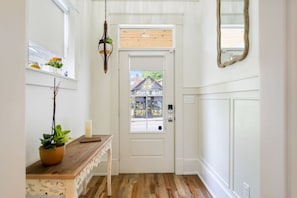 A hallway with a white door, a wooden floor, a hanging lantern, and a window with a view of a building labeled "North Star".