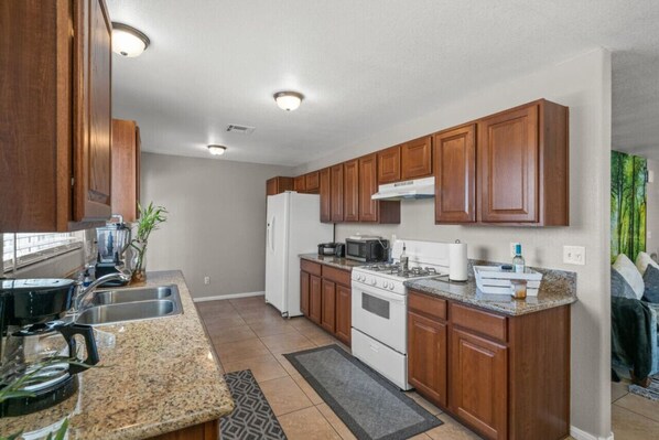A modern kitchen with wooden cabinets, stainless steel appliances, and granite countertops.