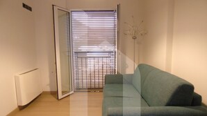 A room with a green sofa, a radiator, and a door with blinds. - Homiday - Emma Residence (Giulianova)