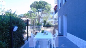 A patio with a white table and chairs, surrounded by a fence and greenery. - Homiday - Emma Residence (Giulianova)