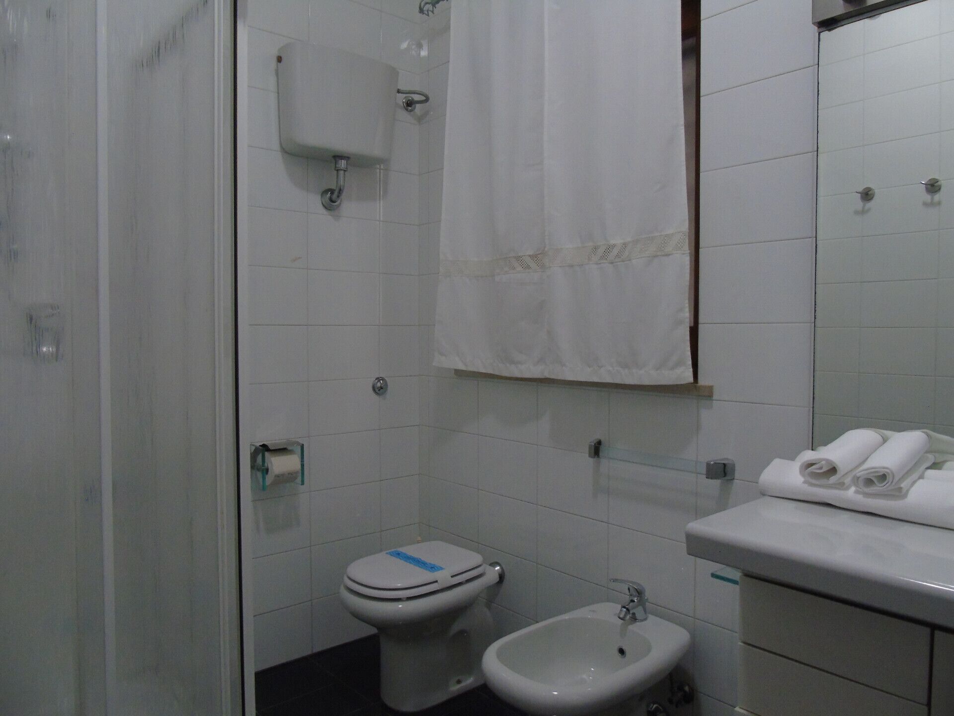 A small, clean bathroom with a toilet, bidet, and sink.