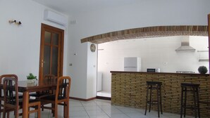 A kitchen with a brick backsplash, white tiles, a refrigerator, a microwave, and a gas stove. - Homiday - Il Moro Residence (Roseto degli Abruzzi)