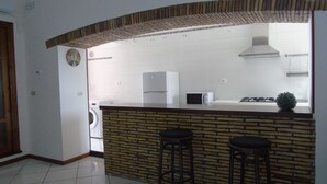 A compact kitchen with a built-in island, a washing machine, and a microwave. - Homiday - Il Moro Residence (Roseto degli Abruzzi)