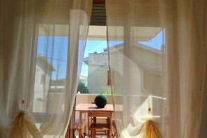 A room with a table and chairs, a small potted plant, and a view through sheer curtains. - Casa Ingrid is an exclusive solution, in the heart of the tourist area of Scerne, about 5 km from the center of Pineto. The entrance leads to a large living room with a fully equipped kitchen with access to the well-equipped balcony to enjoy time o (Pineto)