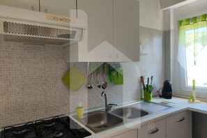 Una cocina moderna con estufa a gas, pileta doble y salpicadero de azulejos.
