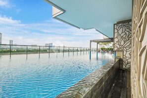 A rooftop infinity pool with a city view, a covered seating area, and a decorative wall. - Alba by Kozystay - 2BR - Tebet (Jakarta)