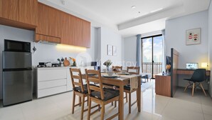 Una cocina moderna con armarios de madera, un refrigerador de acero inoxidable y una zona de comedor con sillas y una mesa de madera.