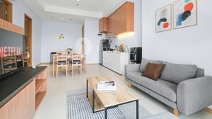 Una sala de estar moderna con un sofá gris, una mesa de centro de madera y un televisor sobre un mueble de madera.
