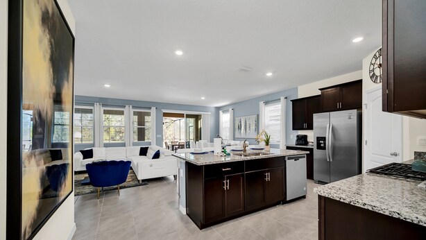 A modern kitchen with dark cabinetry, a stainless steel refrigerator, and a granite countertop. - Luxurious 6BR villa in Davenport with Private Heated Pool, Game Room (Davenport)