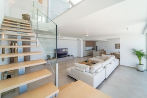Ein stilvoller Wohnbereich mit Treppe, einer Couch, einem Fernseher und einer Küchenzeile.